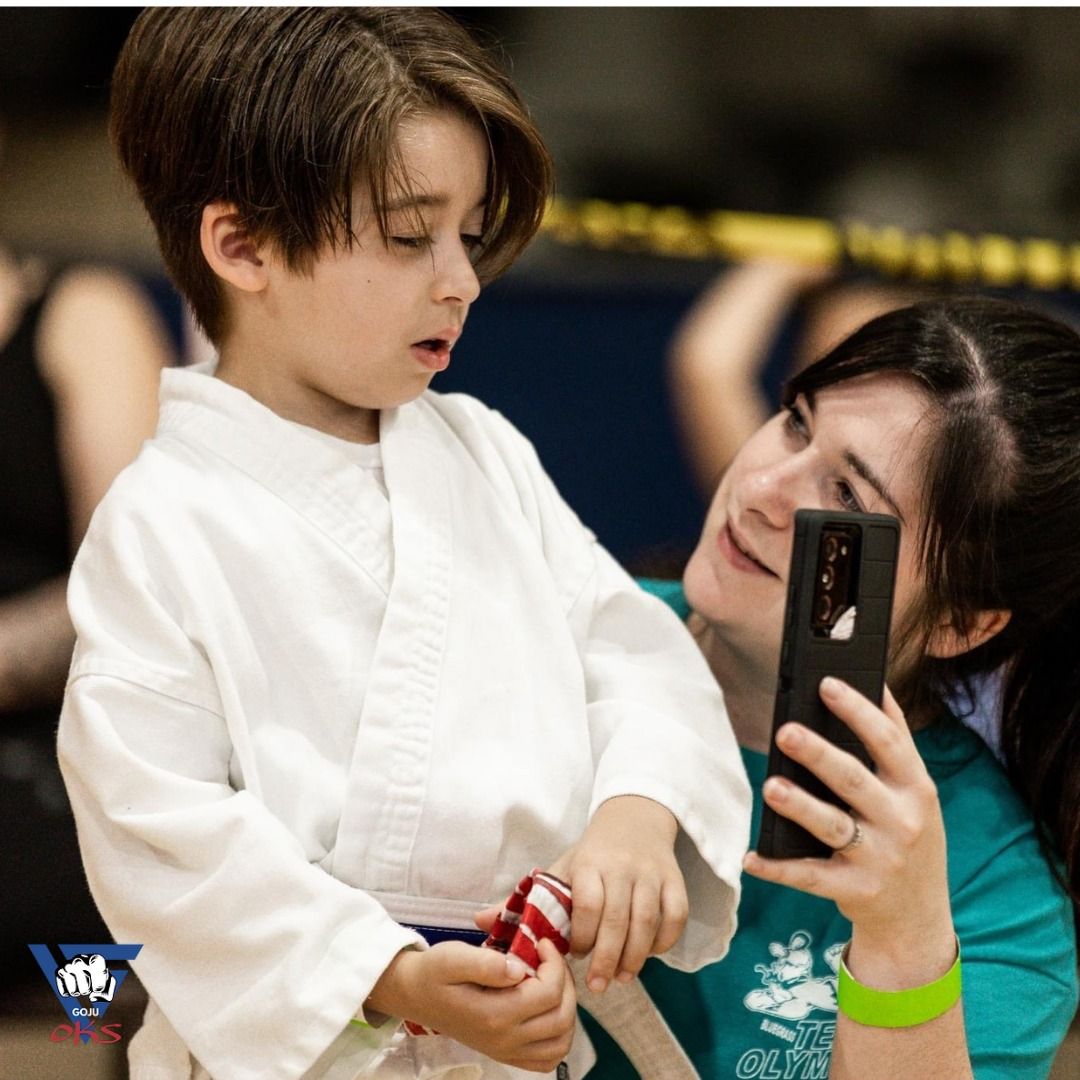 A woman is taking a picture of a young boy with a cell phone