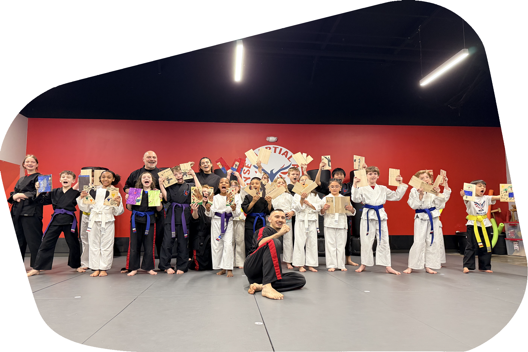 A group of children are sitting on the ground in front of a crowd.