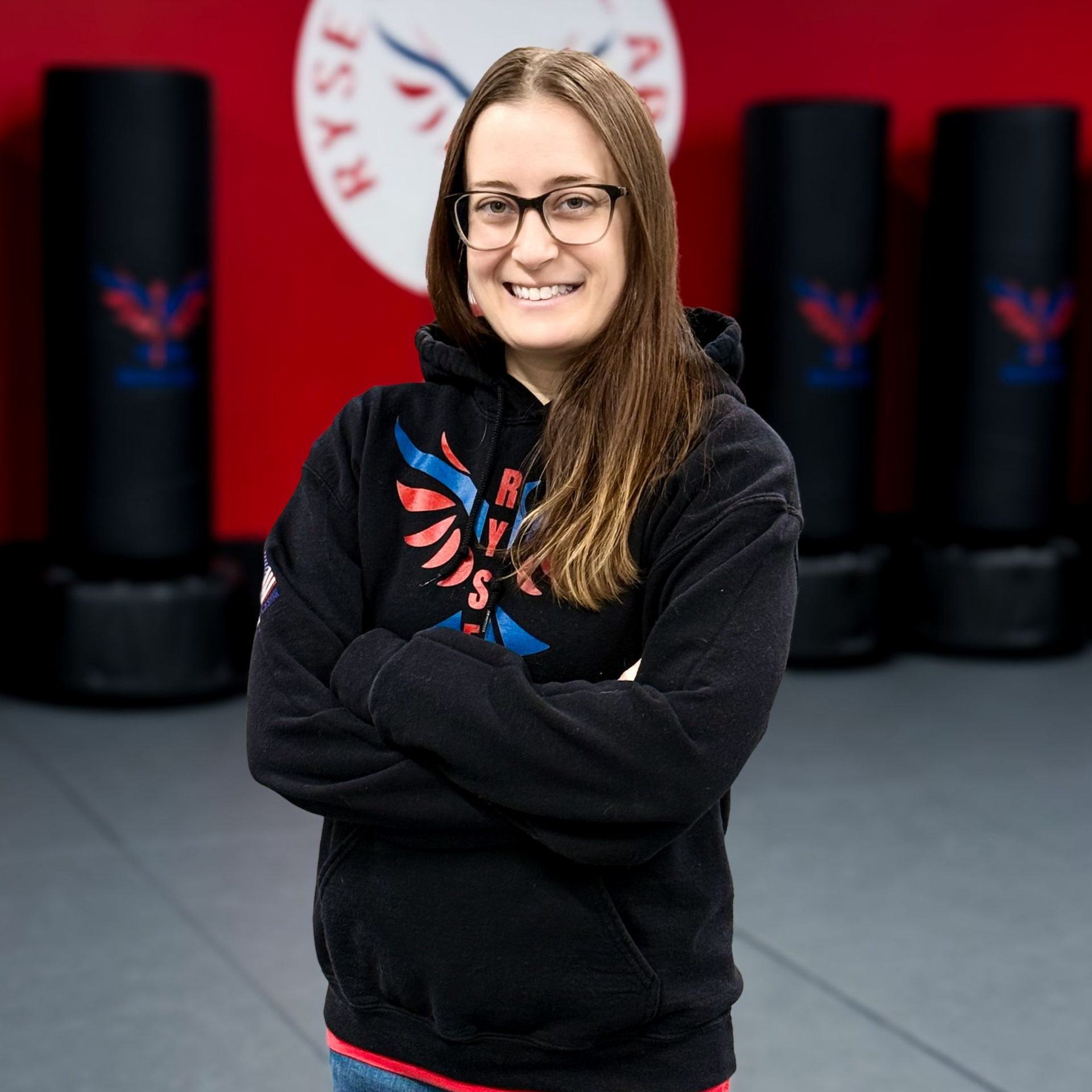 A man in a white karate uniform is standing on a blue mat in a gym.