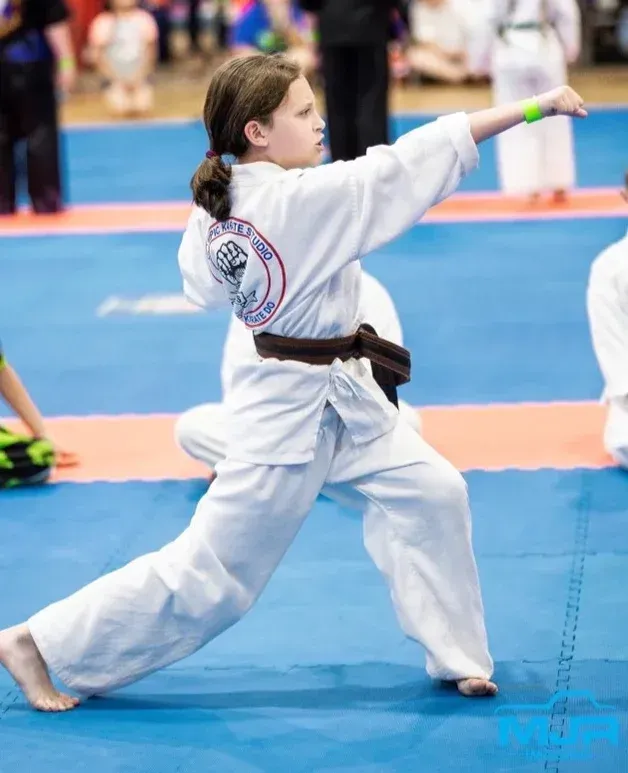 A young girl is practicing karate on a blue mat
