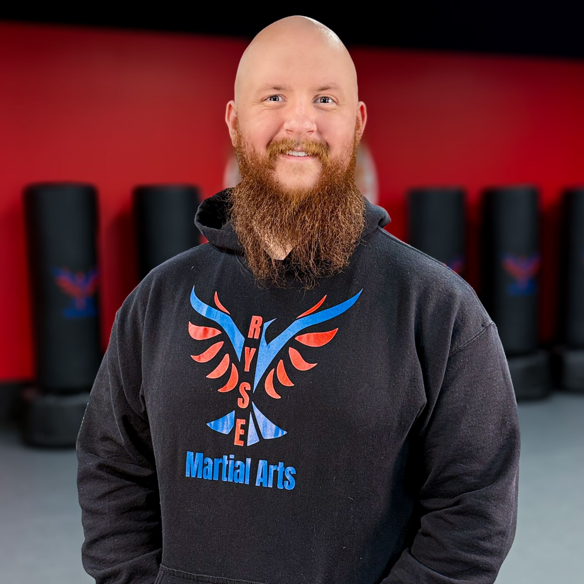 A man in a white karate uniform is standing on a blue mat in a gym.