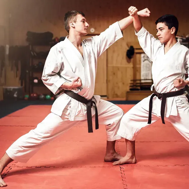 Two young men are practicing karate on a mat