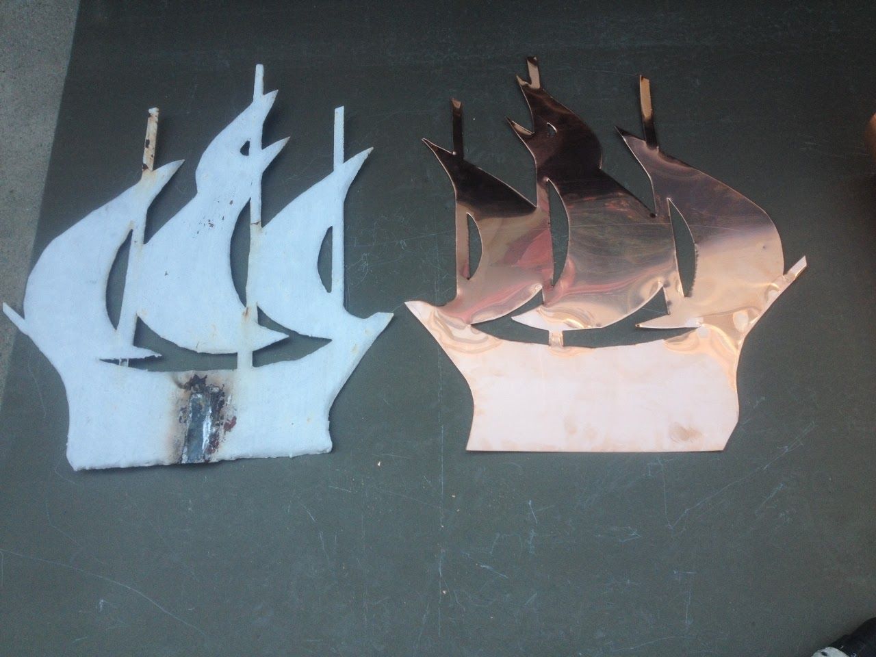 Two metal ship silhouettes: one white, one copper.