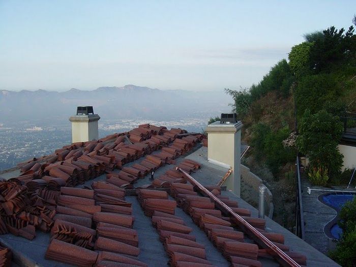 Rooftop with stacked terra cotta tiles, chimney, overlooking valley, mountains, and a pool area.