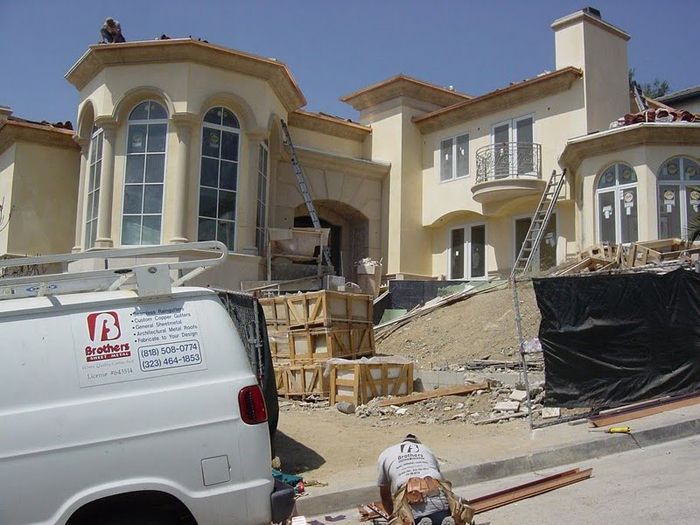 House under construction with scaffolding, van, and workers outside.