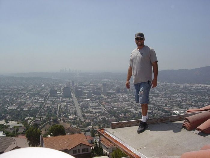 Man standing on rooftop overlooking a sprawling city on a hazy day.
