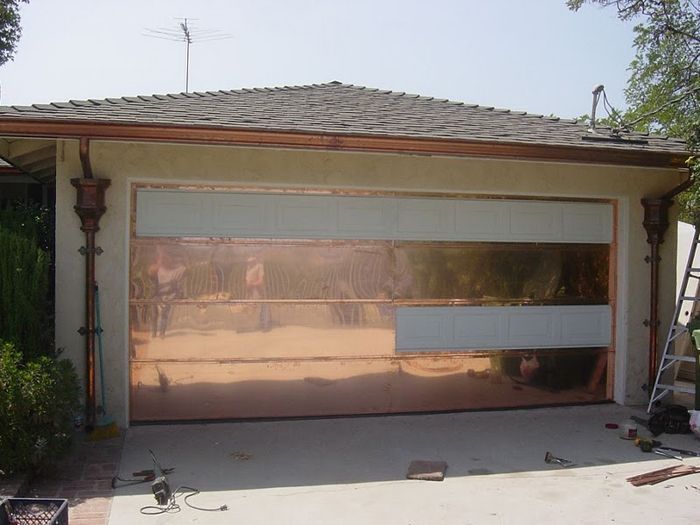 Copper garage door with frosted glass panels. Located on a building with copper gutters and decorative columns.