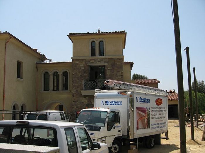 Construction site with a tan building, a work truck, and poles.