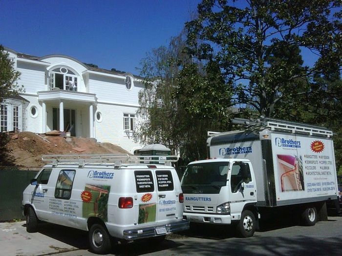 White vans and truck in front of a white house. Services vehicles in a sunny setting.