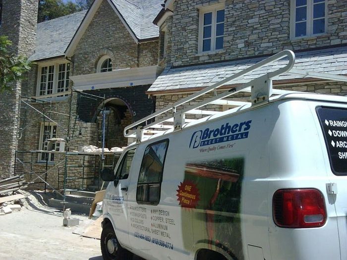 White work van parked outside a large stone house under construction; 
