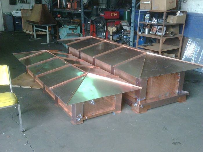 Copper chimney caps assembled in a workshop.