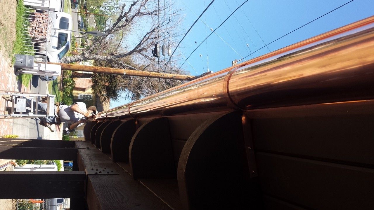 Copper gutters being installed on a building, with a worker visible.