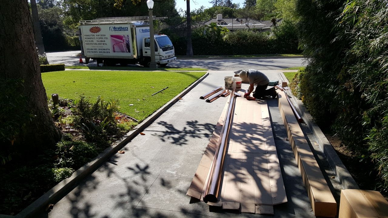 Man unloading wooden planks from a truck on a sunny driveway.