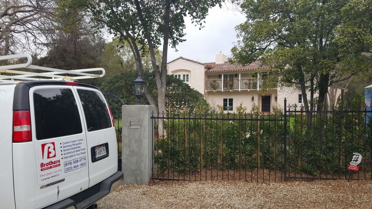 White van parked, fence in front of a light-colored two-story house.
