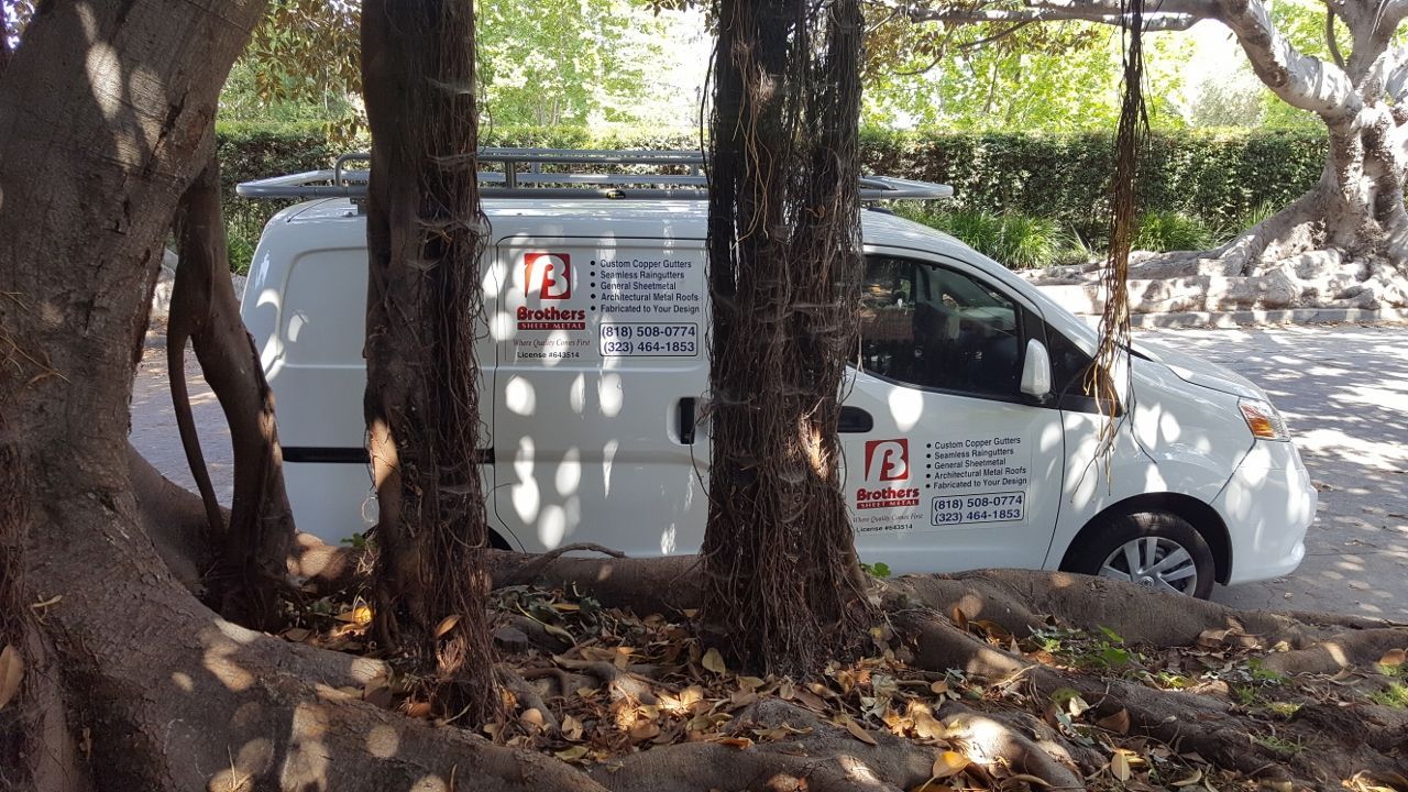 White work van parked near trees.