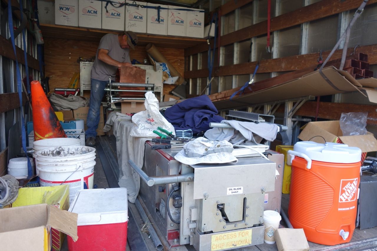 A person inside a cluttered truck. Orange cone, cooler, and equipment visible.