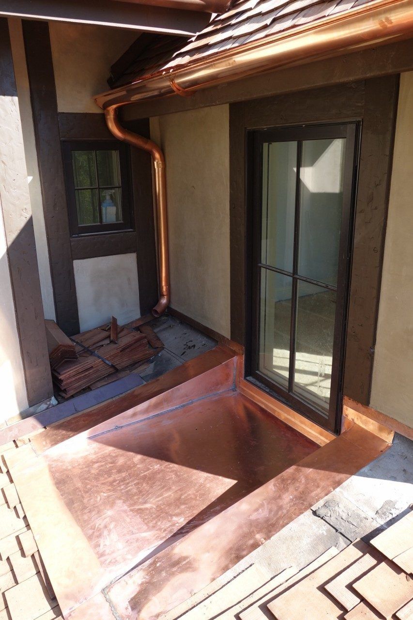 Copper gutters and flashing on a home with a dark-framed window.