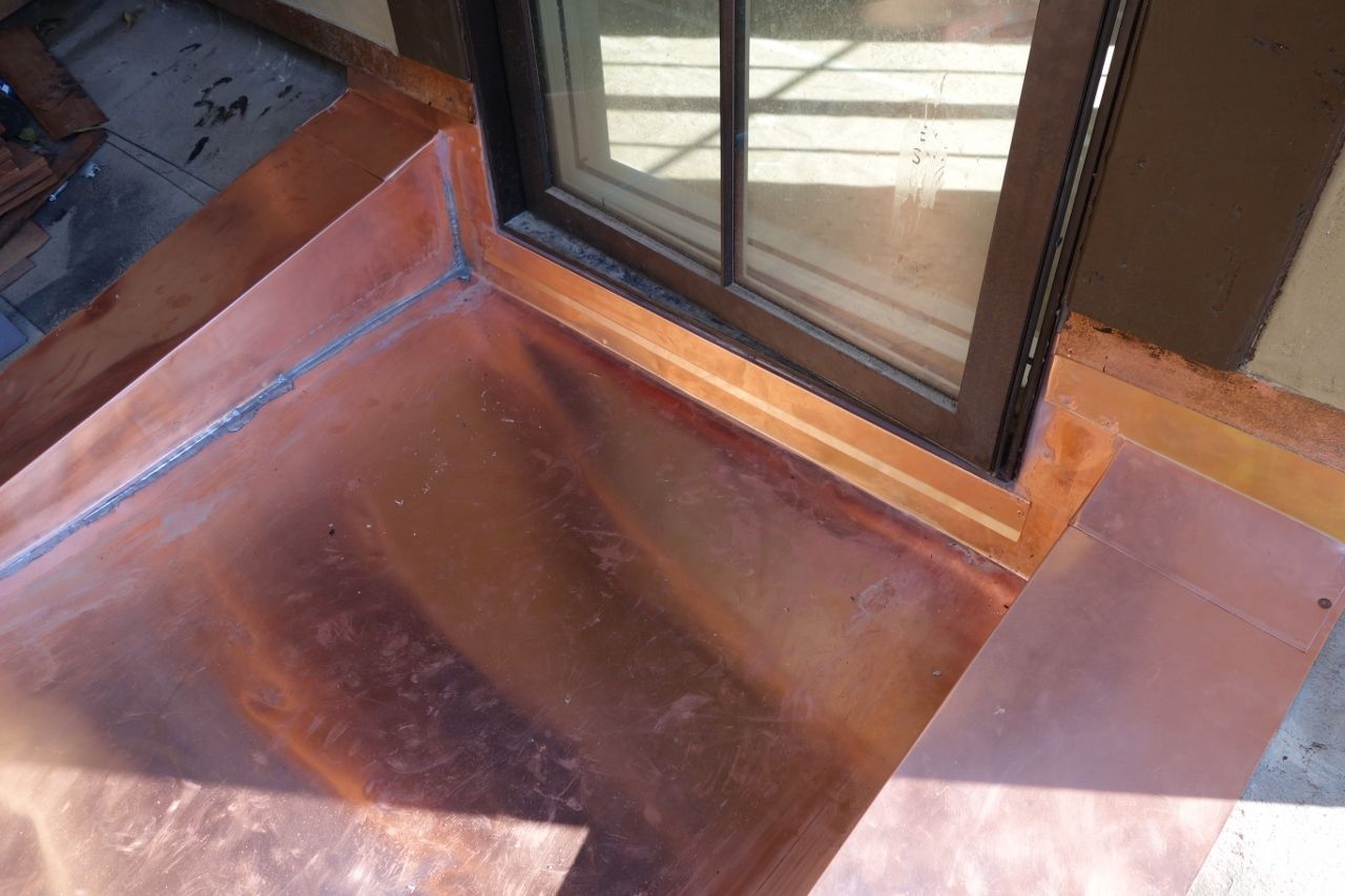 Copper flashing installed around a window frame.