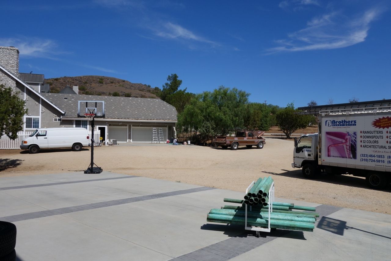 A house with a basketball hoop in the driveway and a truck with moving boxes parked nearby.