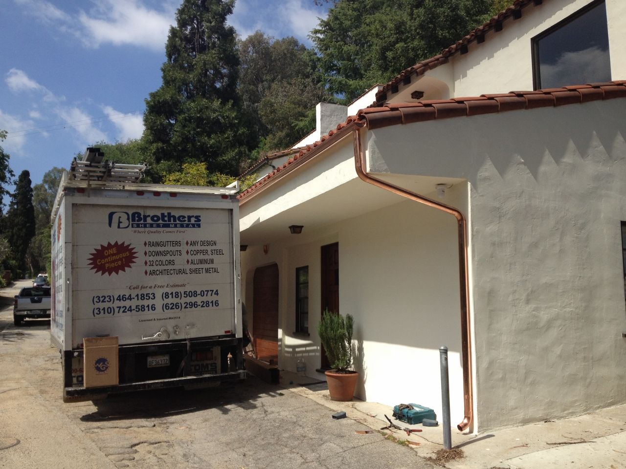 Moving truck parked by a white stucco house with red roof tiles. A delivery is in progress.