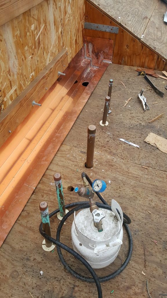 Propane tank, gas lines, and regulator are on a wooden surface, likely an exterior roof or platform.