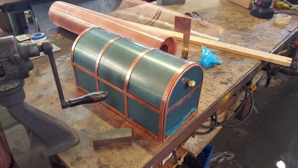 A teal chest with copper trim sits on a workbench, surrounded by copper materials and tools.
