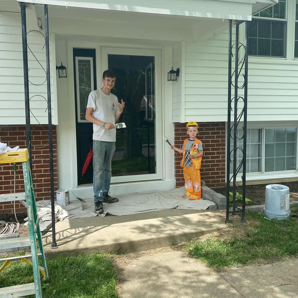 A man is painting a window on the side of a house.