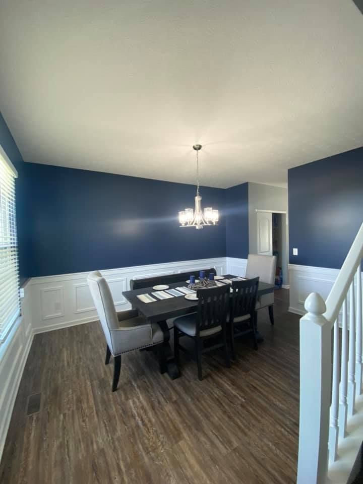 A man is painting a wall in a room with a roller.