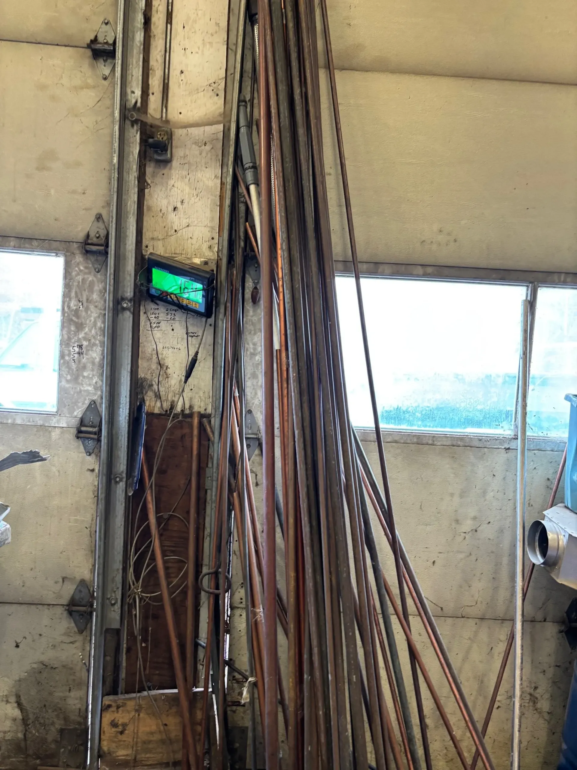 A bunch of metal pipes are stacked on top of each other in a garage.