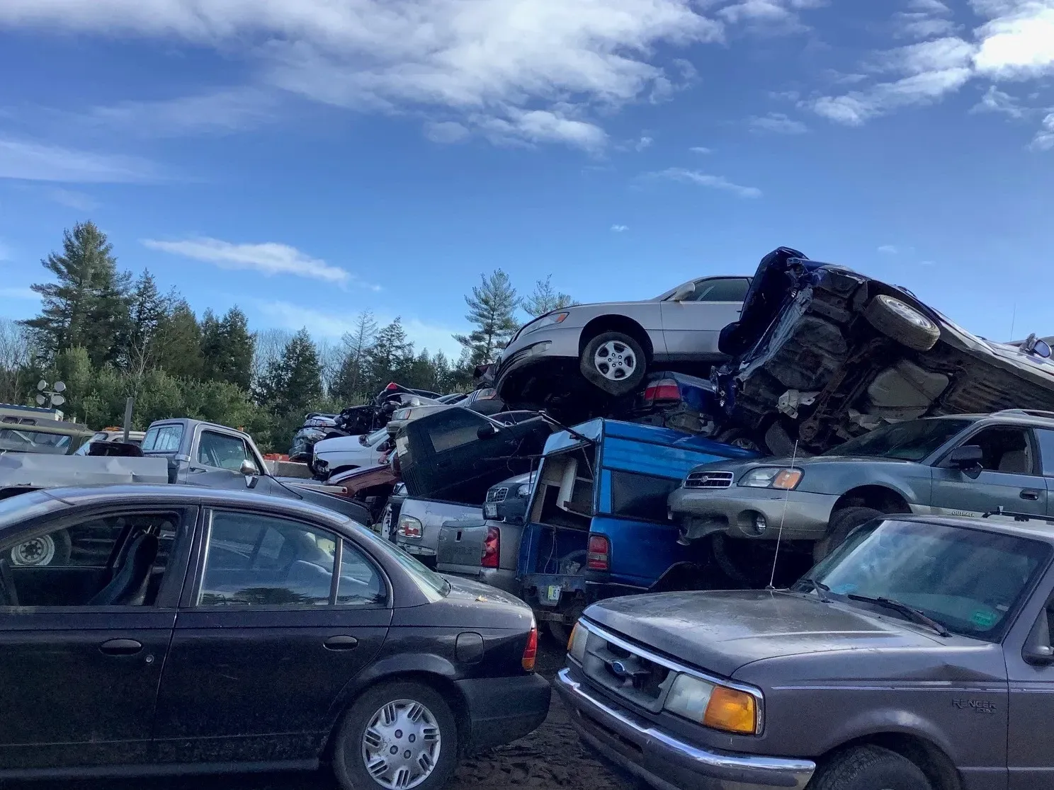 A bunch of cars are stacked on top of each other in a junkyard.