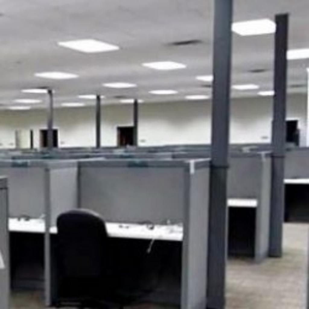 A large empty office with cubicles and a chair.
