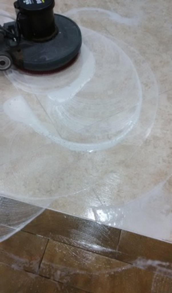 A person is cleaning a tile floor with a machine.