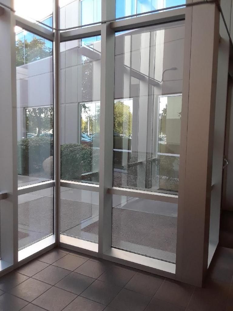 A room with a lot of windows and a reflection of a building in the windows.