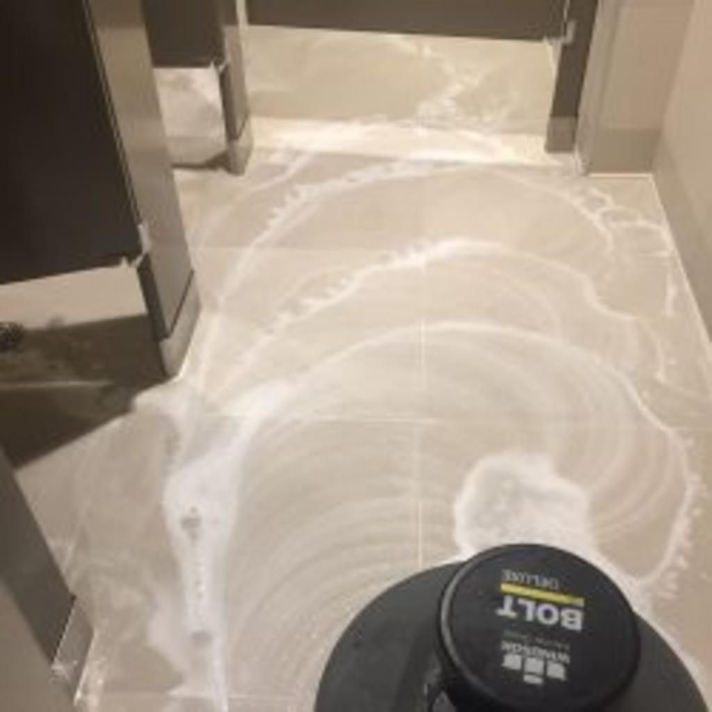A machine is cleaning a tile floor in a bathroom.