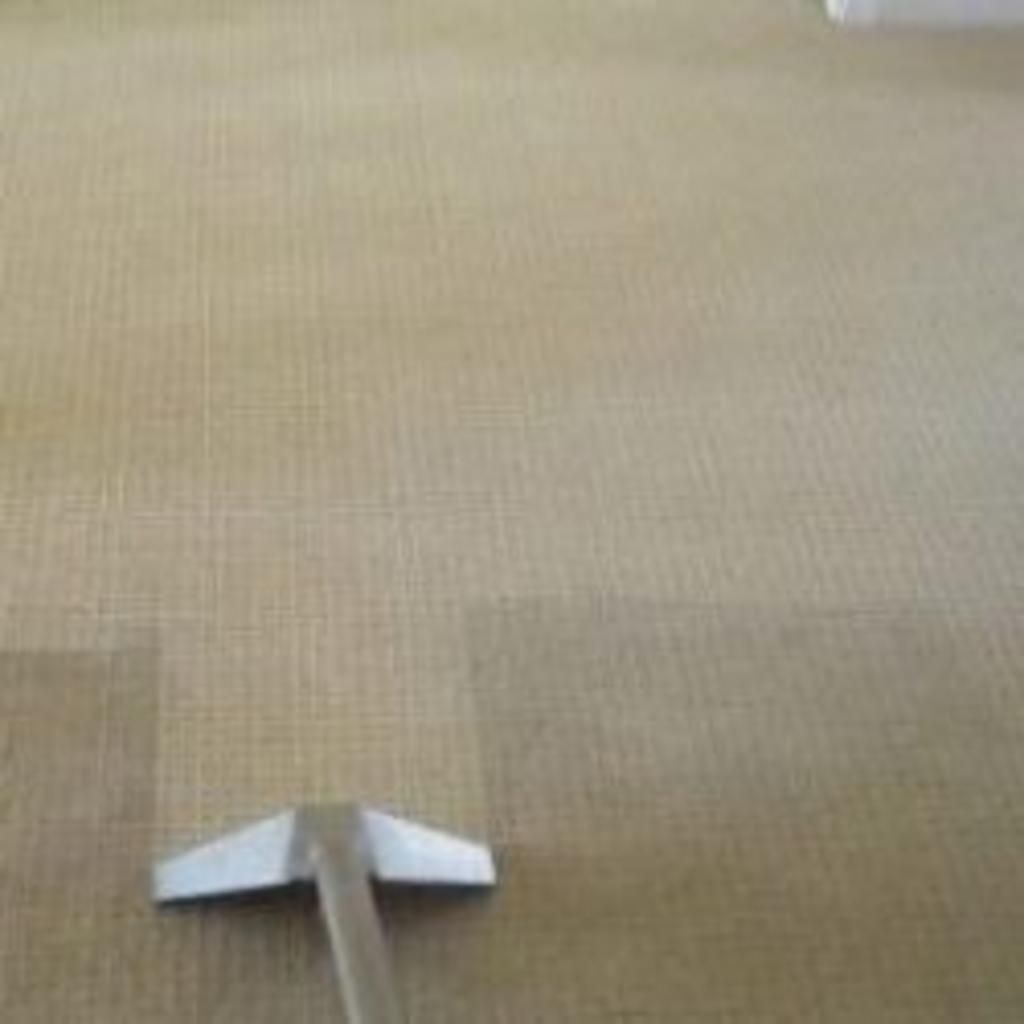 A vacuum cleaner is cleaning a carpet in a room.