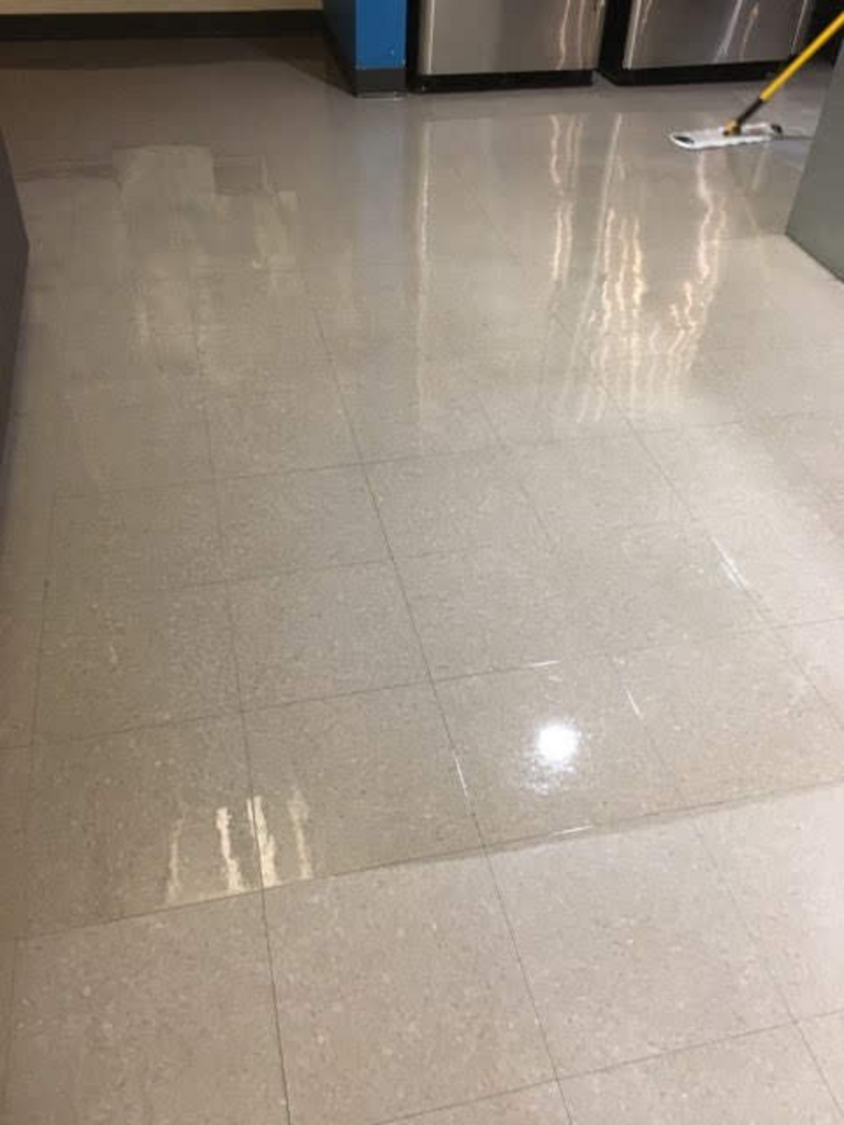 A mop is being used to clean a tiled floor in a room.