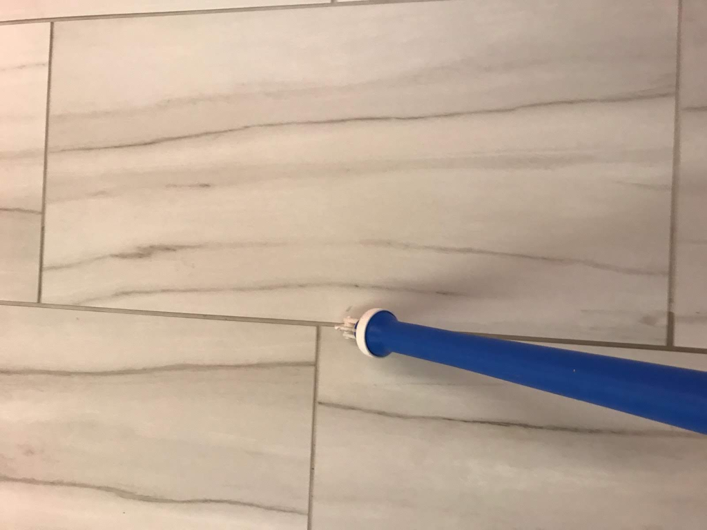 A blue baseball bat is sitting on a tiled floor.
