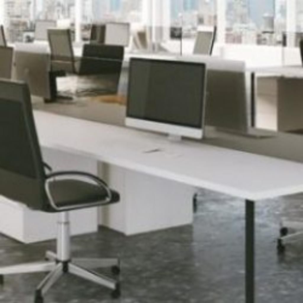 There are many computers on the desks in this office.