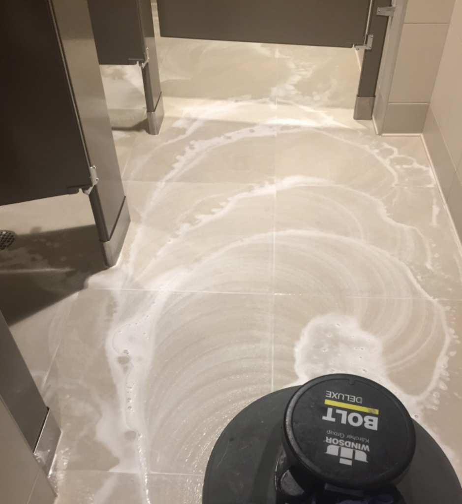 A black bolt machine is being used to clean a tiled floor