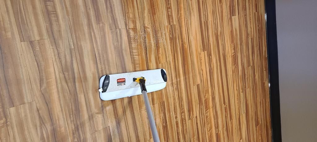 A person is cleaning a wooden floor with a mop.
