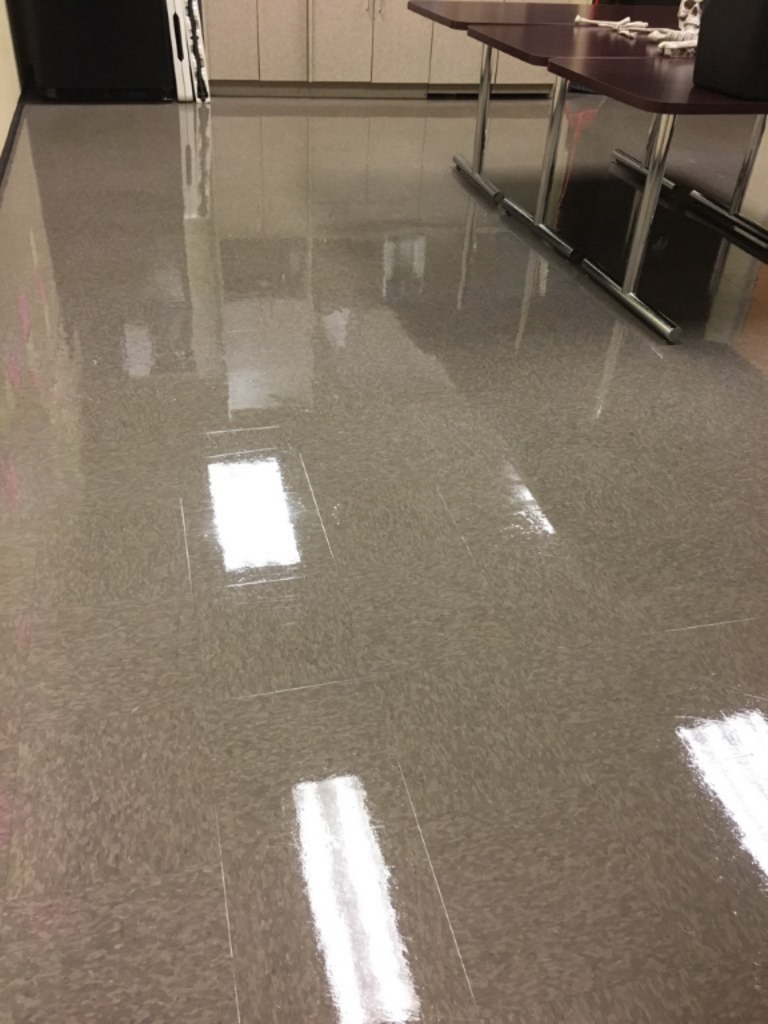 A shiny tiled floor in a room with a table and chairs.