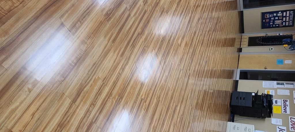 A wooden floor in a room with a bulletin board.