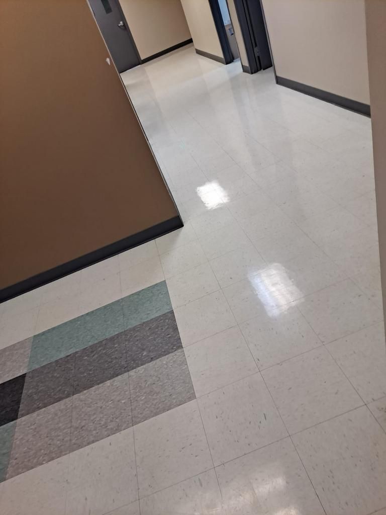 A hallway with a white tile floor and brown walls.