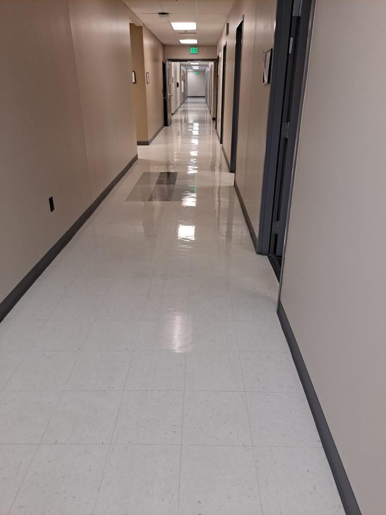 A long hallway in a building with a white tile floor.