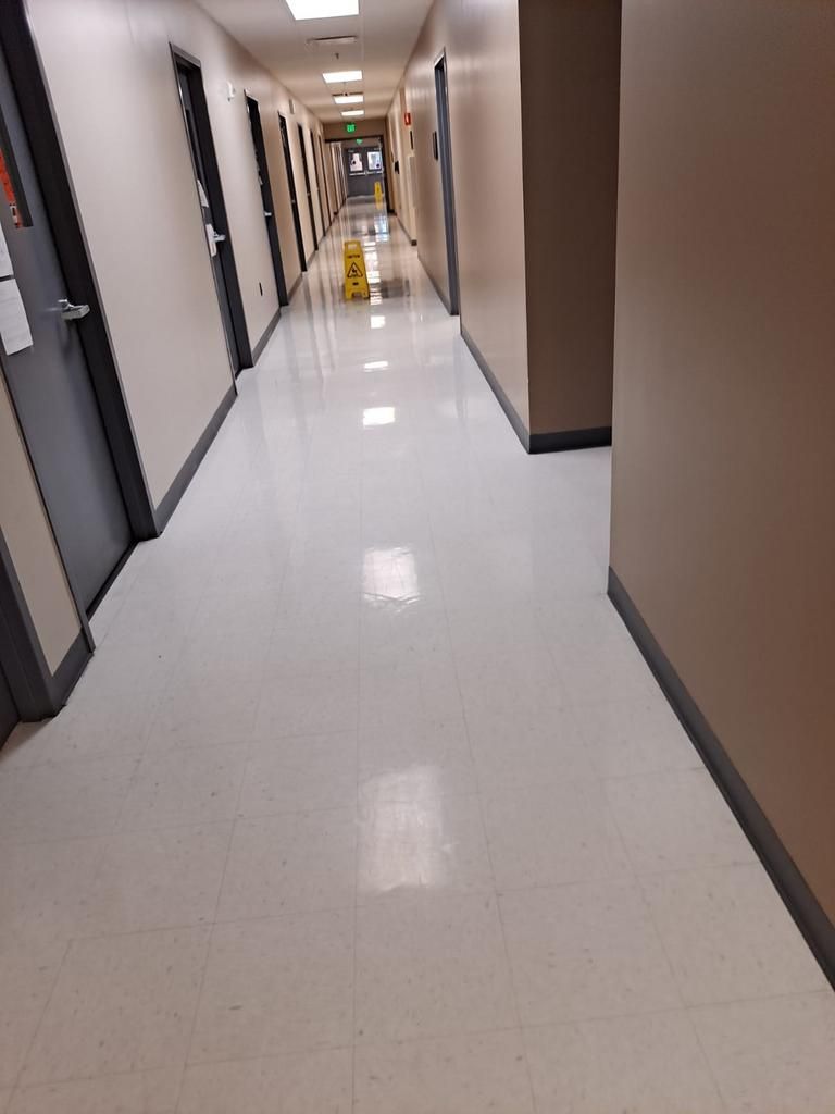 A long hallway with a yellow wet floor sign on the floor.