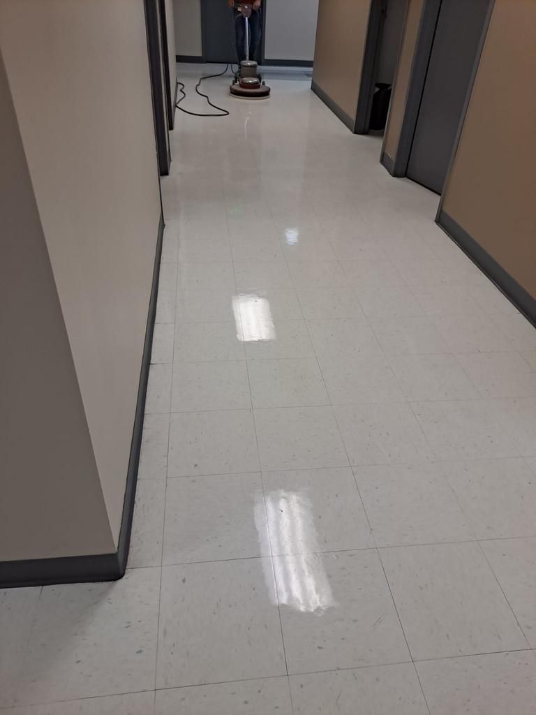 A person is cleaning the floor of a hallway with a vacuum cleaner.