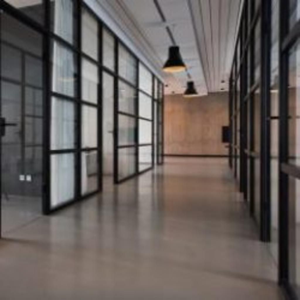 A long hallway with a lot of windows and lamps hanging from the ceiling.