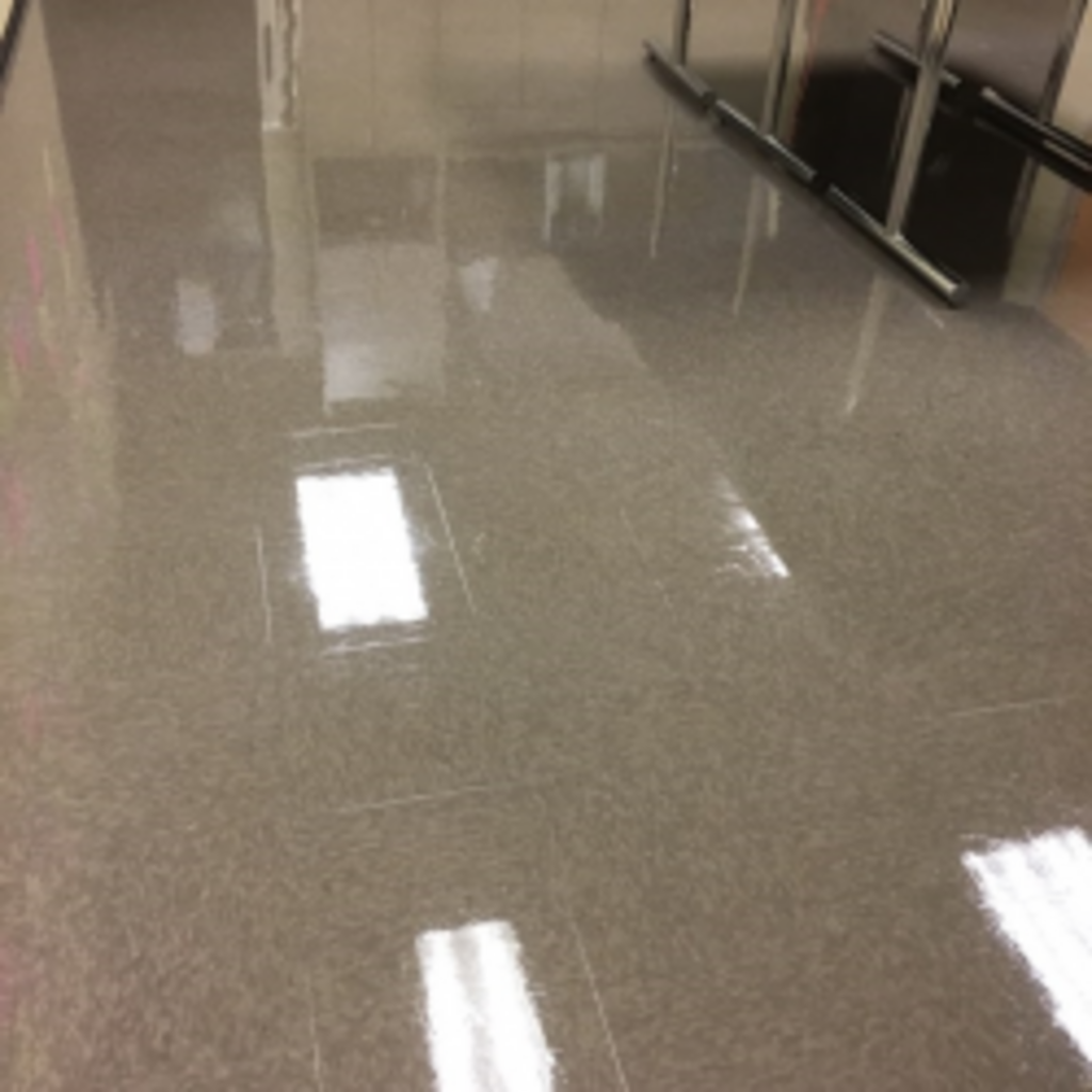 A shiny tiled floor in a hallway with a reflection of lights.