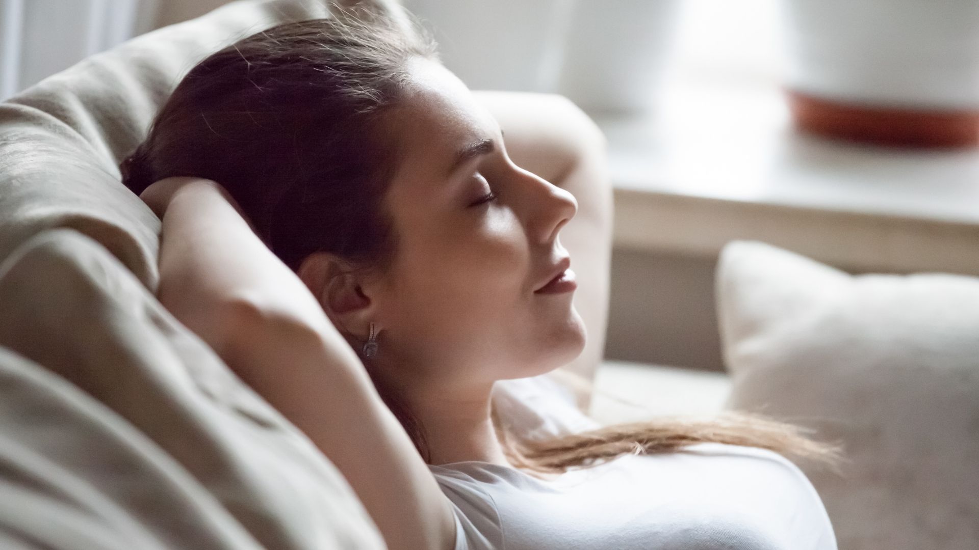 A woman is laying on a couch with her eyes closed.