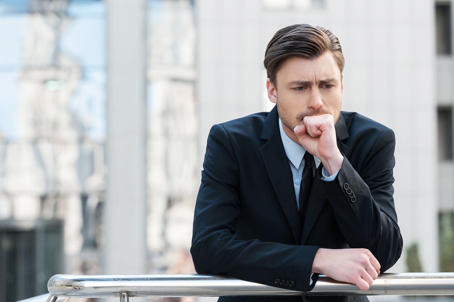 A man in a suit and tie is leaning on a railing.
